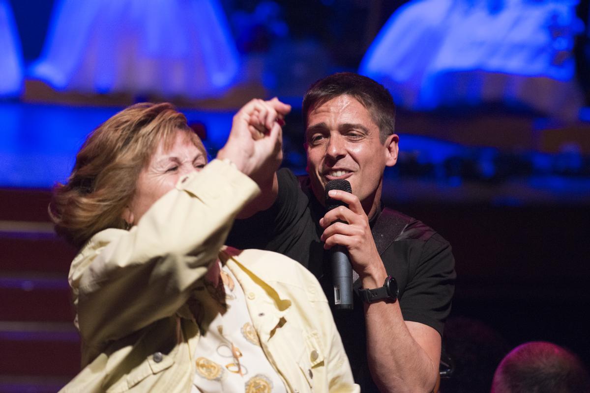 El presentador de la gala cantando y bailando con una mujer del público.