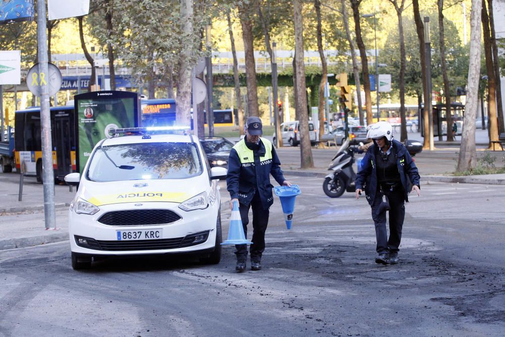 Carrers amb restes de mobiliari urbà cremat, contenidors per terra i treballadors de la brigada treballant