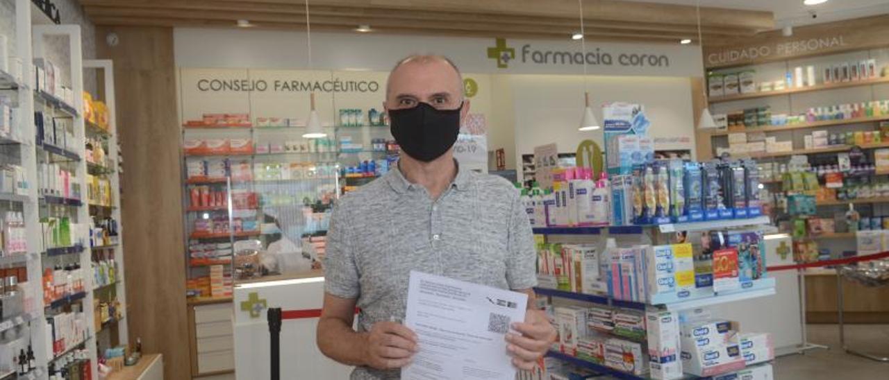 Un vecino de Vilanova muestra el certificado de vacunación expedido en la farmacia de Caleiro.