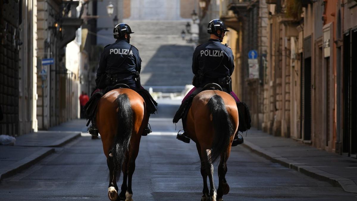 Dos policías a caballo patrullan por las calles vacías de Roma.