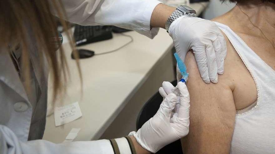 Una sanitaria vacuna contra la gripe a una paciente en un ambulatorio de A Coruña.