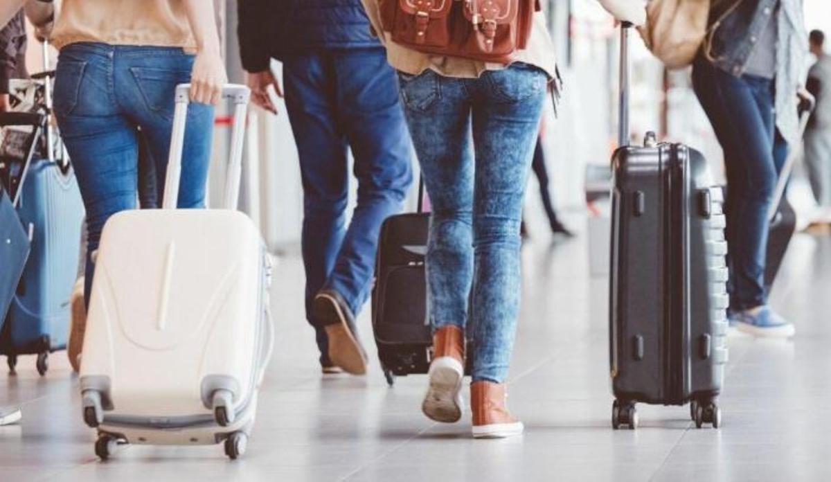 Unos pasajeros con sus maletas en el aeropuerto.