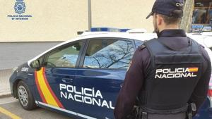 Un agente de la Policía Nacional junto al coche policial.