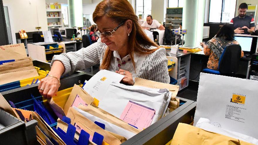 Una empleada de Correos busca un paquete en la oficina principal de la capital grancanaria, en Primero de Mayo.