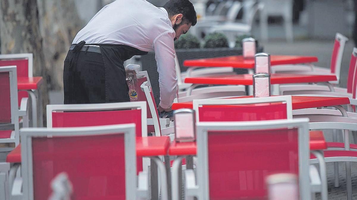 Un camarero, limpiando las mesas de una terraza