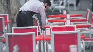 Un camarero, limpiando las mesas de una terraza