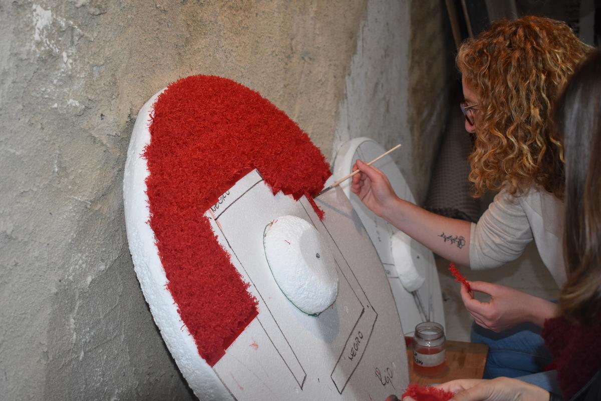 ntegrantes de una de las carrozas que participarán en el Anunci se reparten el trabajo para plegar, cortar y rizar el papel, así como otros elementos de su creación. )