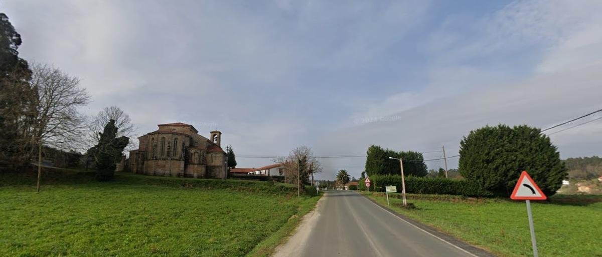 Un tramo de la carretera en el que se construirá una senda peatonal y, al fondo, la iglesia de Cines.