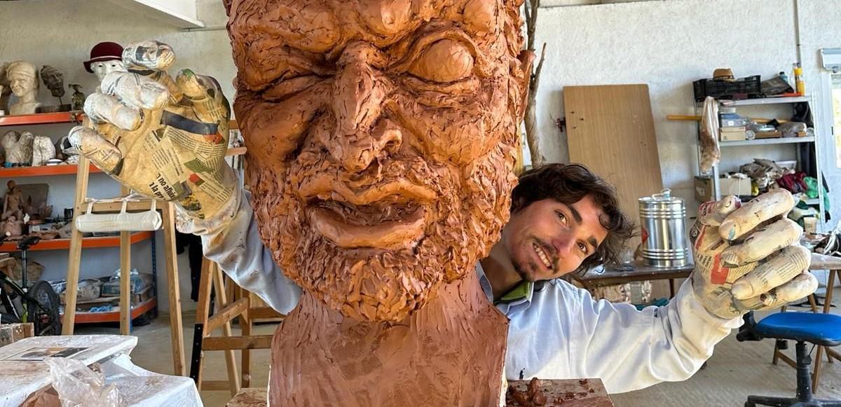L'artista solsoní fa broma amb les mans d'una de les figures que crea