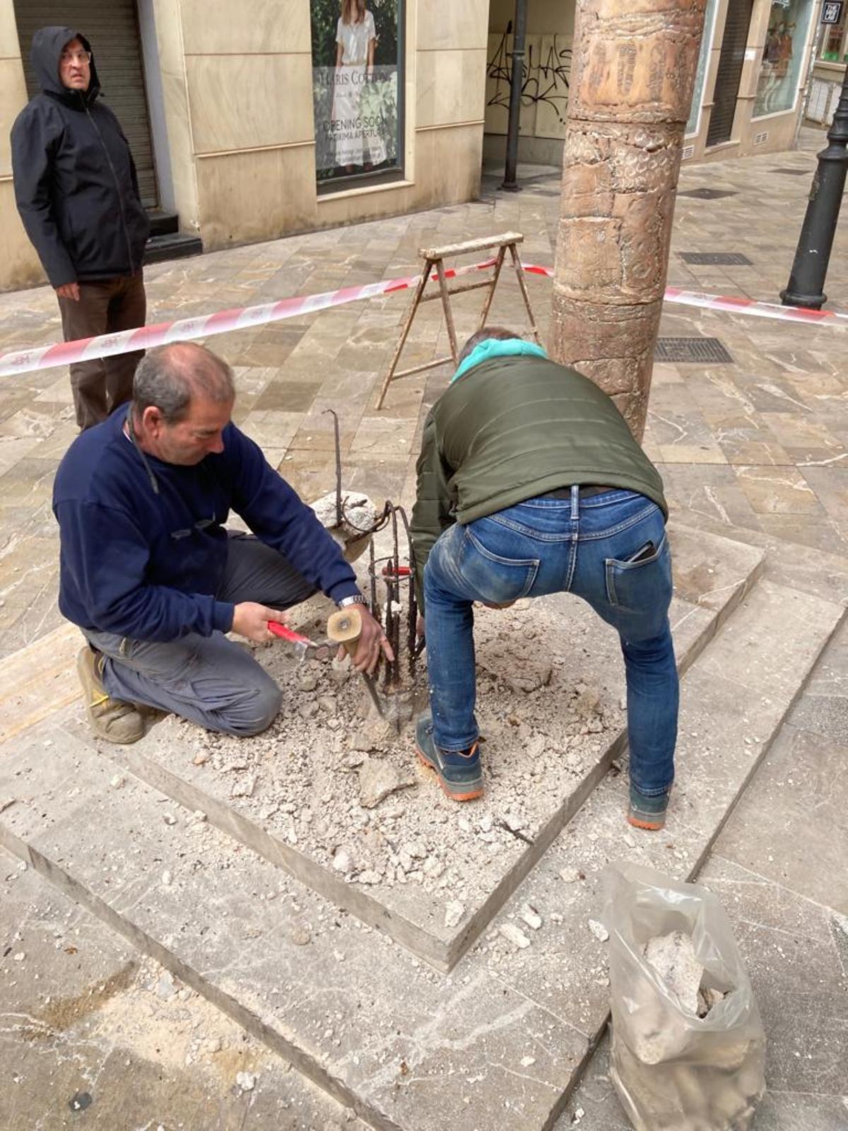 Los técnicos reparando la escultura.