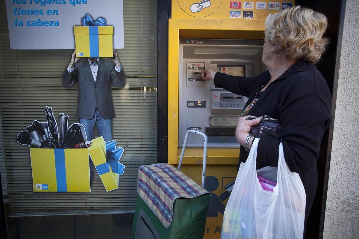 Una mujer saca dinero en un cajero.