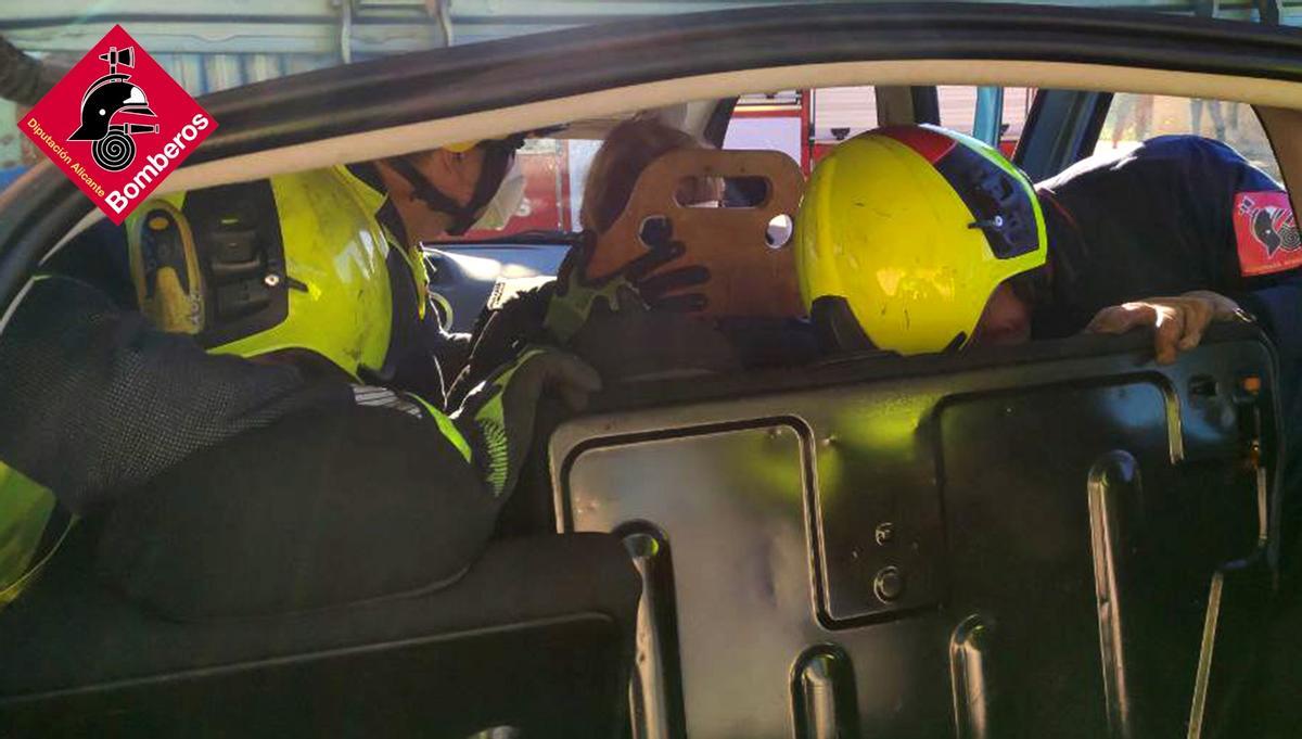 Los bomberos durante el rescate de la mujer atrapada en el coche tras el accidente ocurrido en Elda.