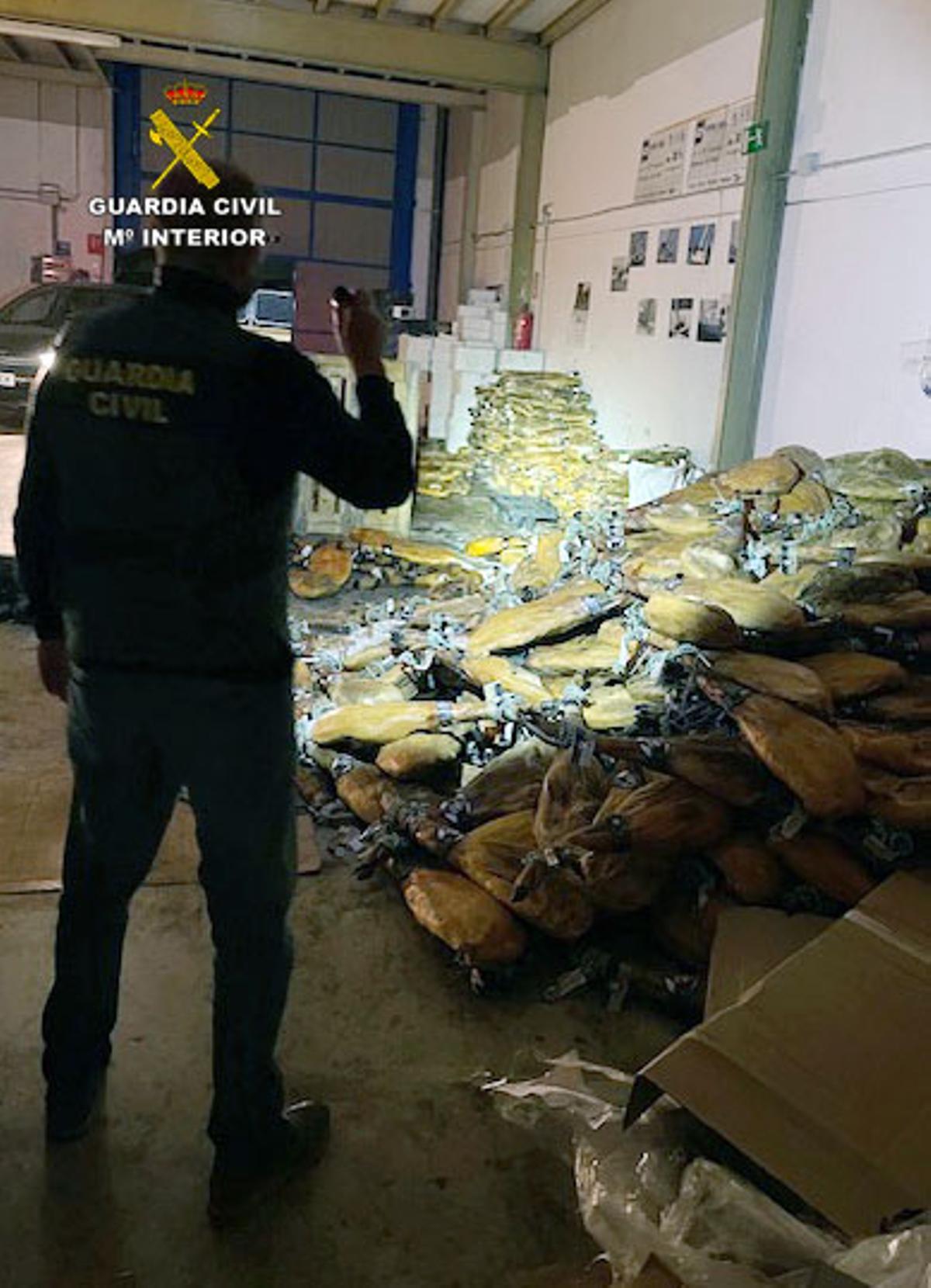 Un agente con parte de los jamones recuperados en Benejúzar.