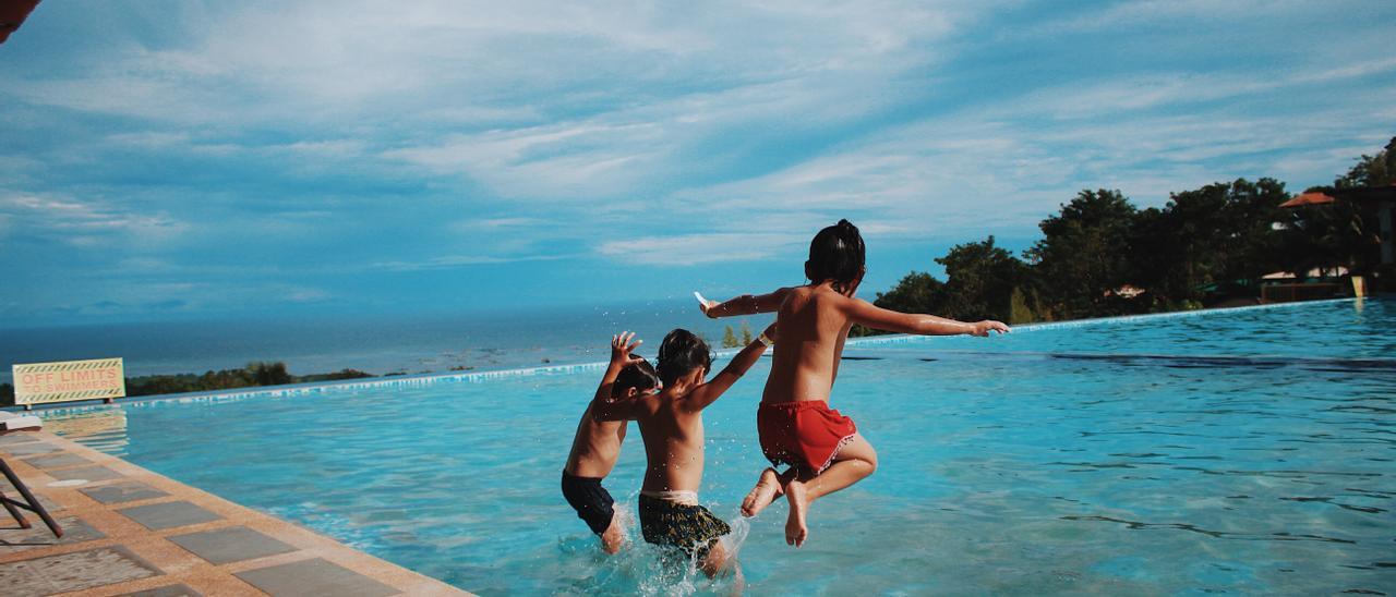 Niños saltando a una piscina.