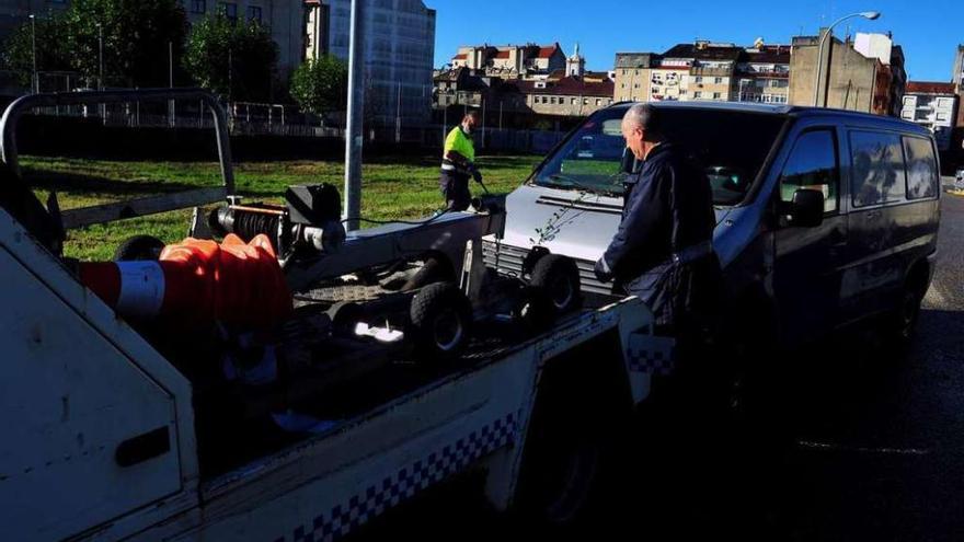 Un vehículo con grúa retirando de la vía una furgoneta mal estacionada. // FdV