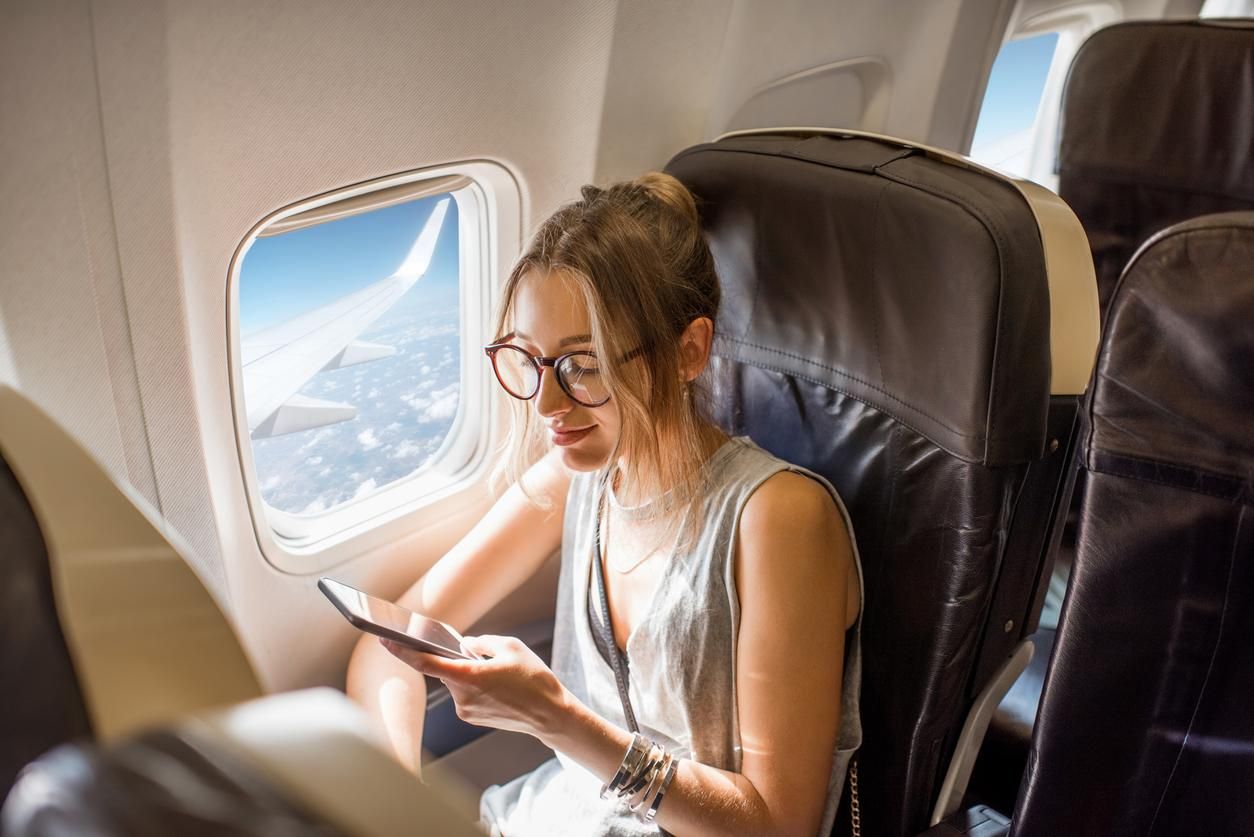 Imagen de una mujer en un vuelo con su teléfono móvil.