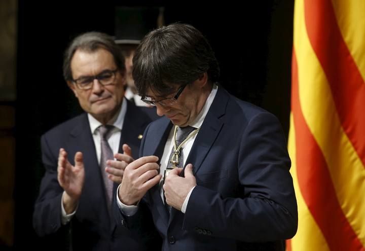 New Catalan President Puigdemont looks down at a medal he received from outgoing Catalan President Mas during Puigdemont's swearing-in ceremony as President of the Generalitat de Catalunya at Palau de la Generalitat in Barcelona