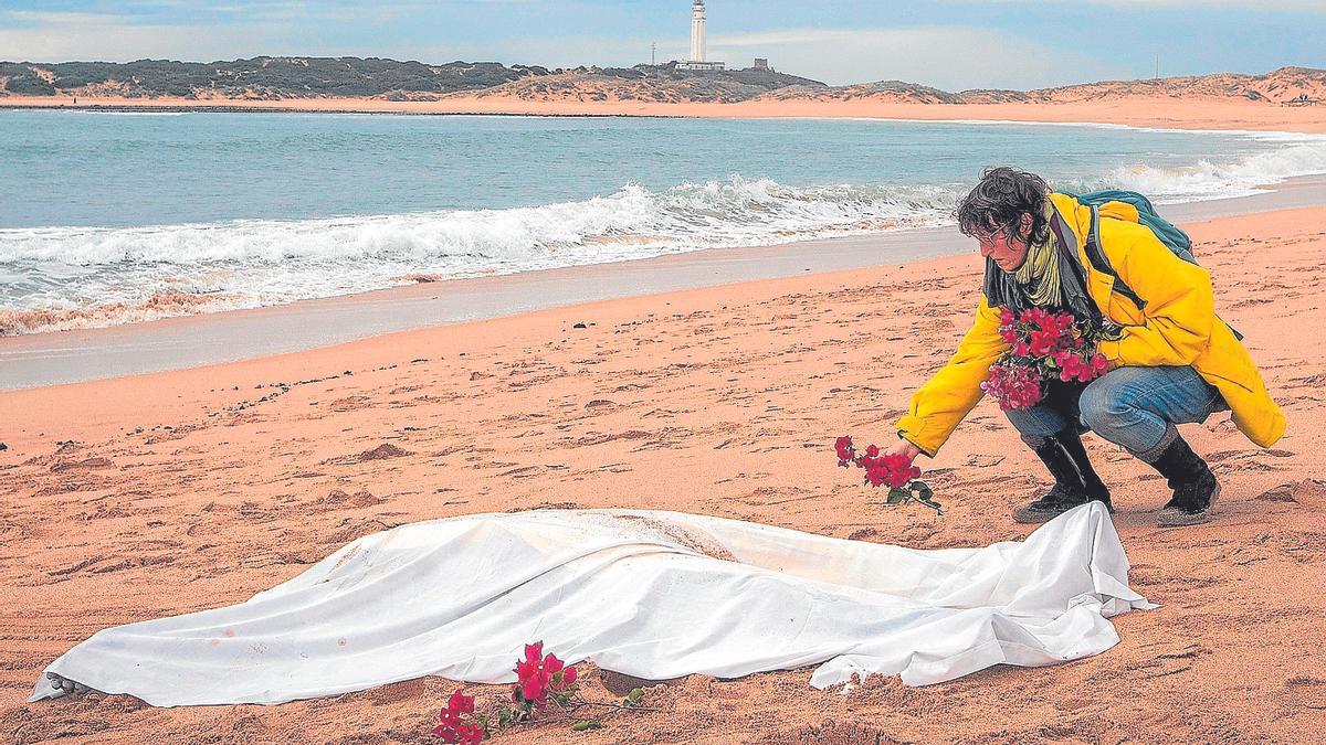 Una mujer coloca unas flores alrededor de otro de los cadáveres aparecidos de los inmigrantes que naufragaron en una patera