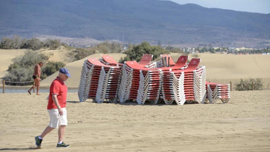 Un turista pasea frente a las hamacas recogidas en la playa de Maspalomas.