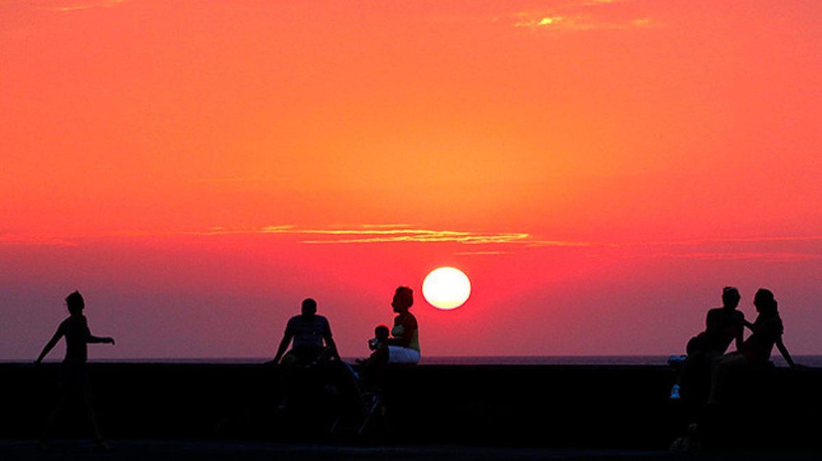 Un grup de cubans seu al capvespre al llarg del Malecón de l’Havana.