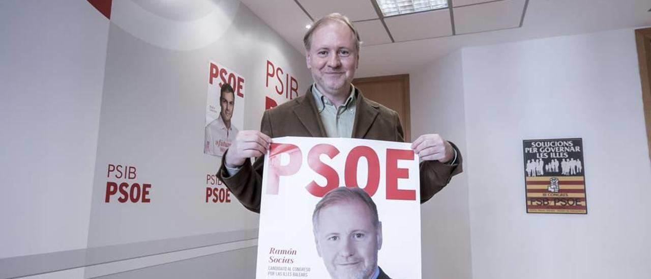 Ramon Socías, candidato del PSOE al Congreso, posa con su cartel electoral en la sede del partido.