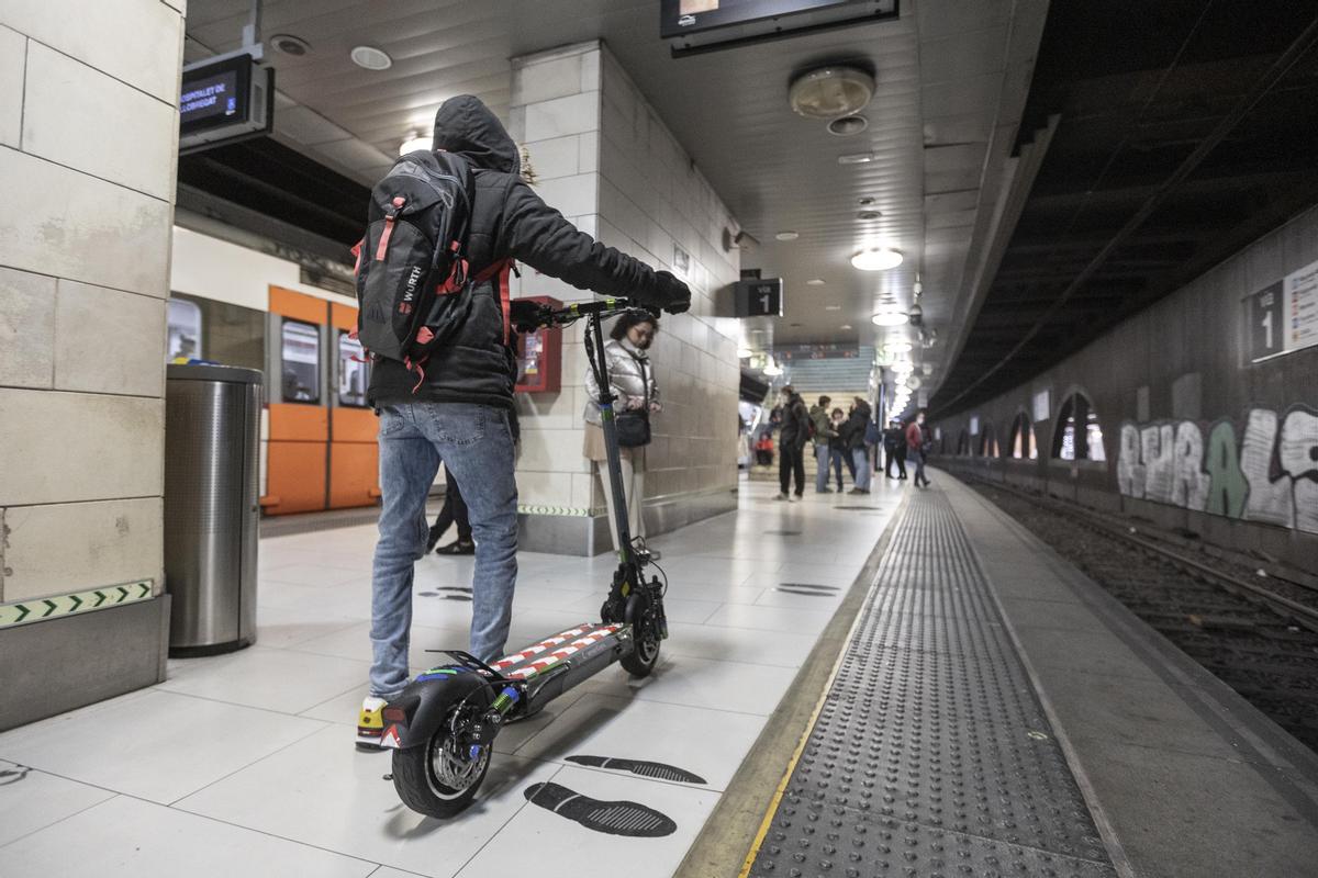 Un viajero con un patinete eléctrico en la estación de plaza Catalunya, el primer día de prohibición en los transportes públicos de Barcelona