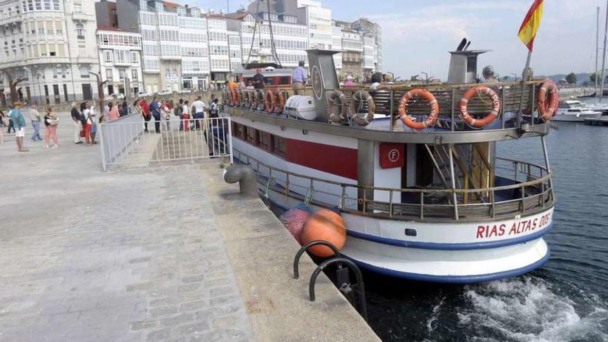 Turistas entran en un barco para visitar la costa coruñesa.