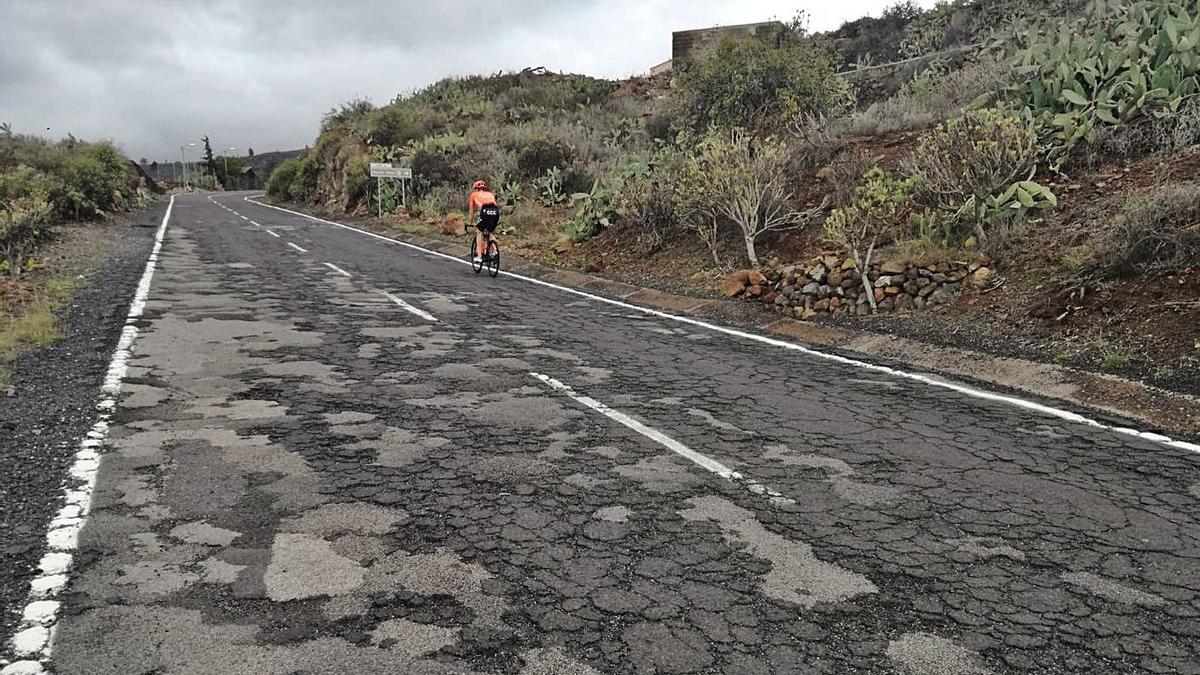 Un ciclista pedalea en un tramo de la TF-565, cuyo estado no hace falta comentar vista la imagen.