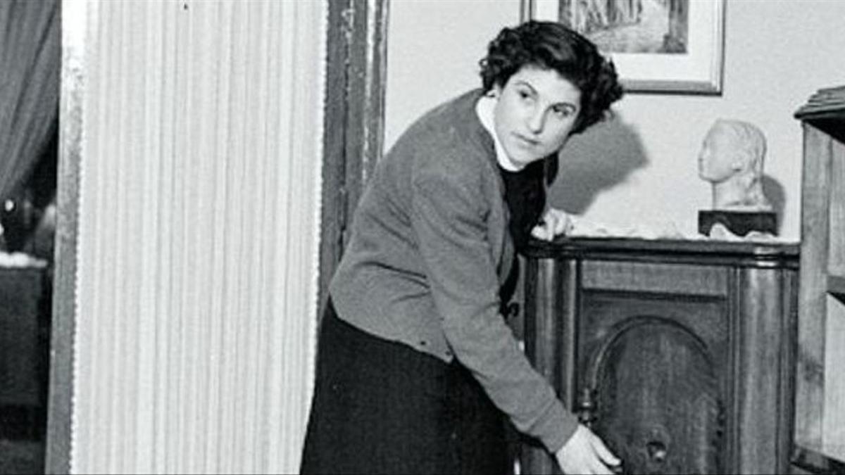 Una mujer enciende una radio de mueble.