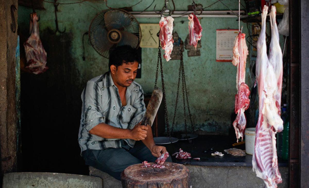 Un home talla carn a la seva botiga de Bombai.