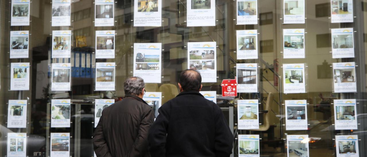 Dos homes consulten anuncis en una agència immobiliària