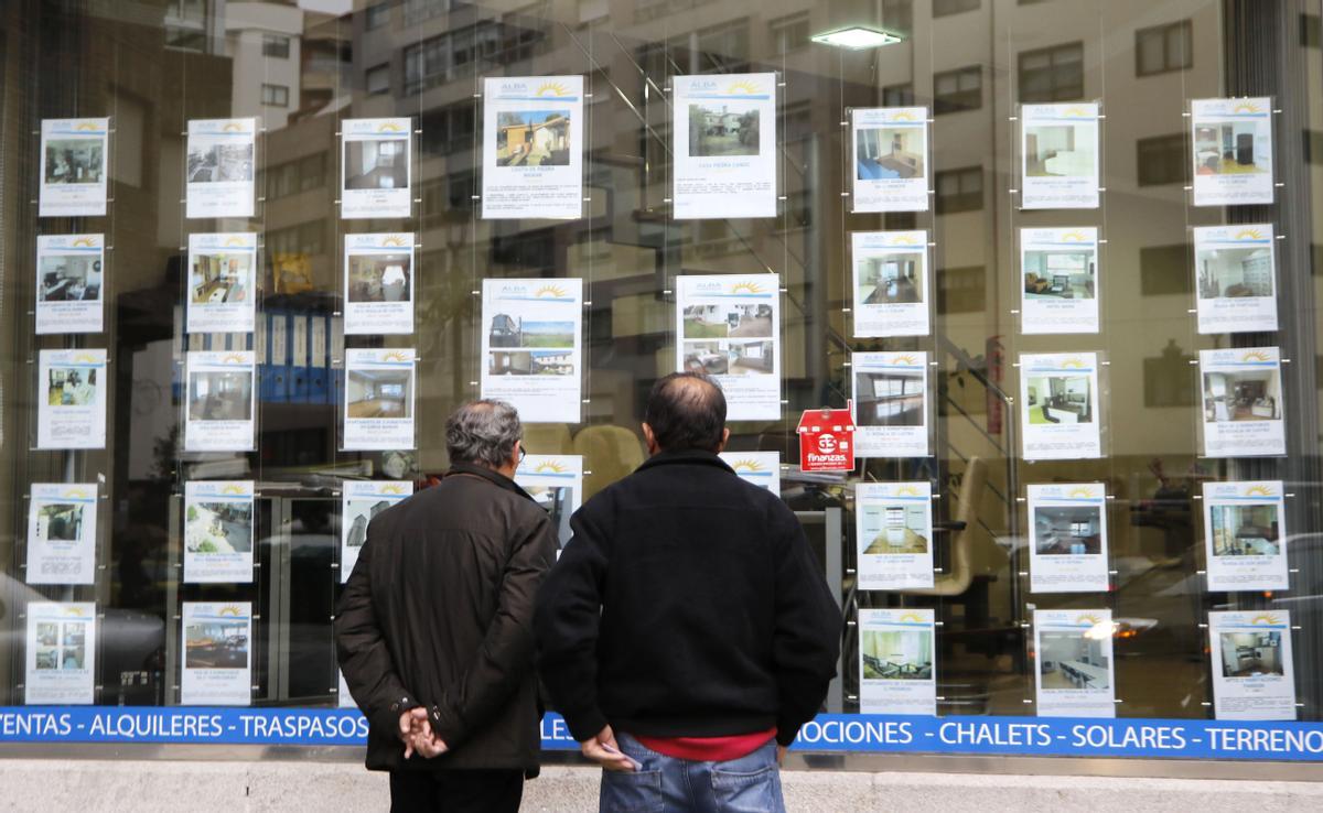Dos homes consulten anuncis en una agència immobiliària