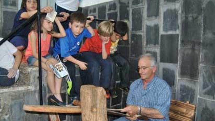 Niños del Aurelio Menéndez observan el trabajo de un cesteiro.