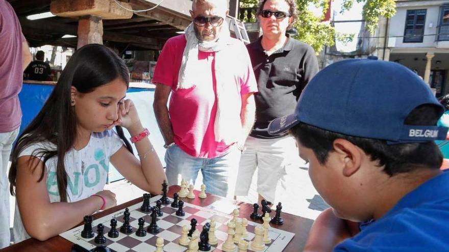 Paula Pérez y Daniela Ruano dibujan para el concurso junto a sus familiares. A la derecha, una partida entre dos de los participantes en el torneo de ajedrez, ayer, en El Carbayedo.