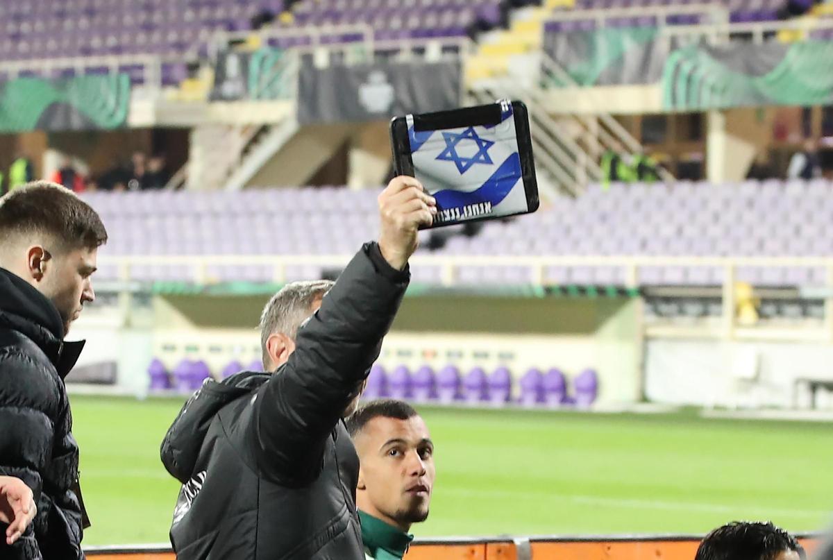 Un miembro del cuerpo técnico del Maccabi Haifa muestra una bandera de Israel en el partido de Conference League frente a la Fiorentina.