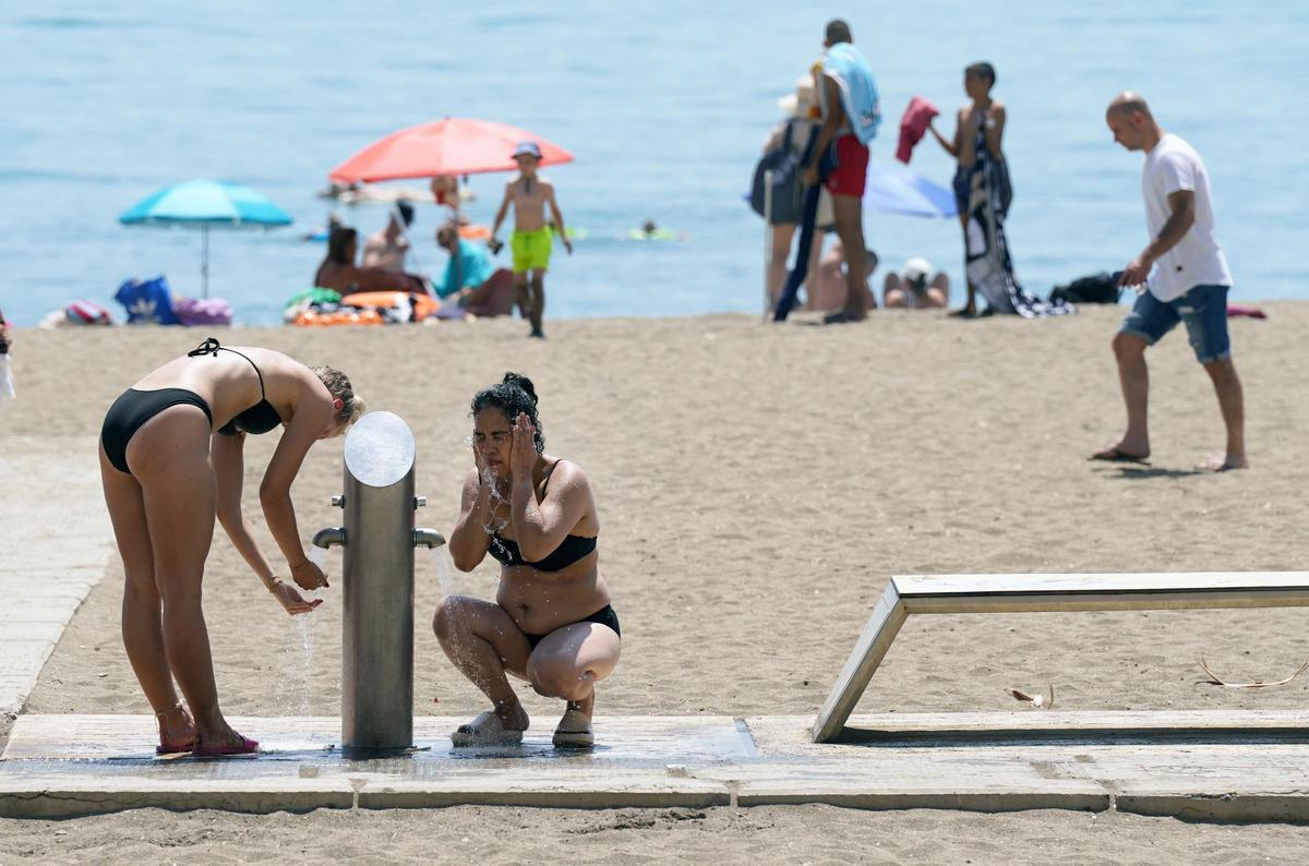 Usuarios de las playas de Málaga usan las duchas y lavapiés días antes de que corten en el agua. Agosto de 2023.