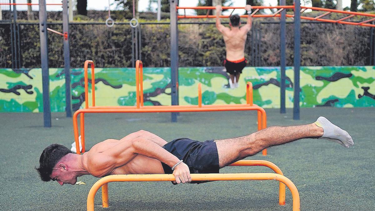 Dos adolescentes realizan ejercicios físicos en un parque al aire libre.