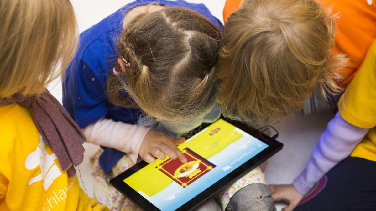 Imagen de archivo de menores mirando una tableta