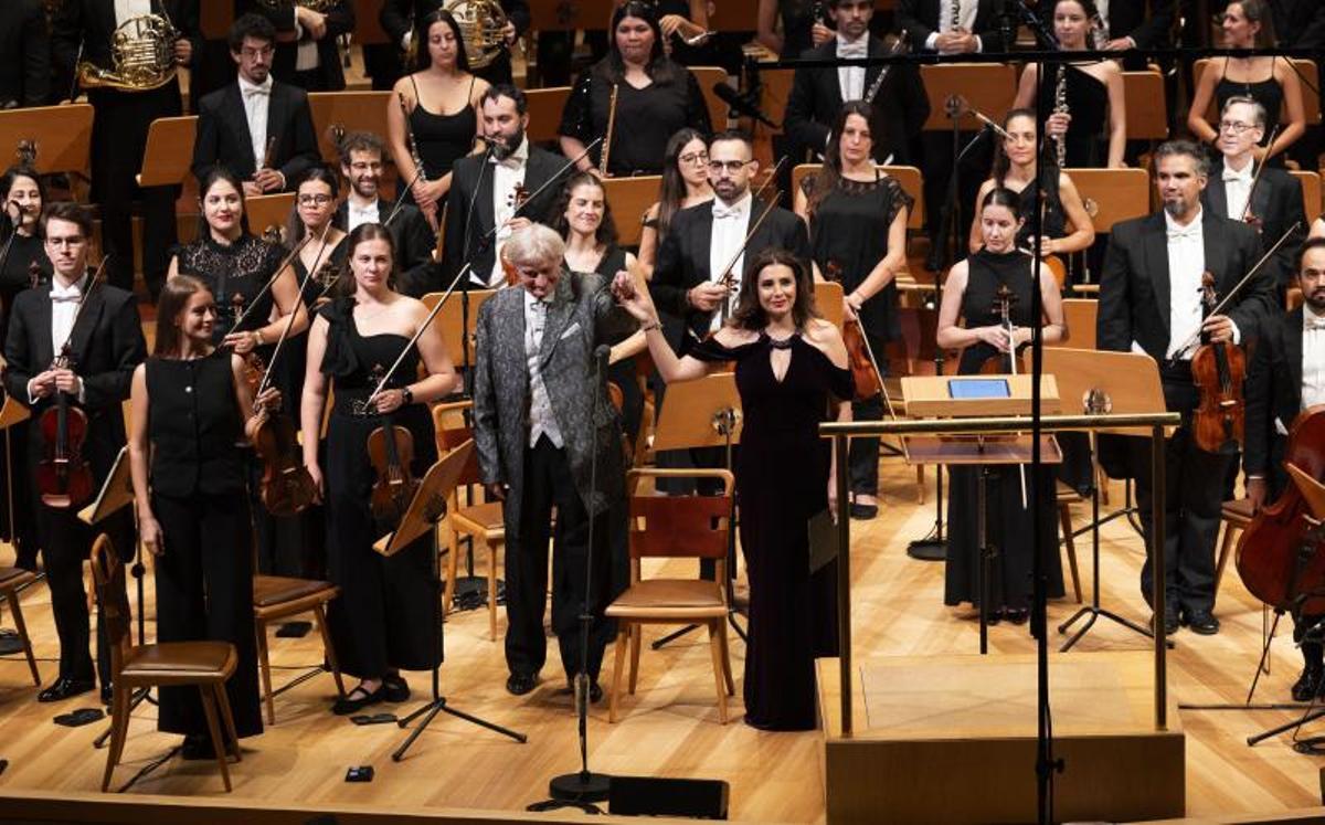 El director Grzegorz Nowak y la soprano Sabina Puértolas saludan al inicio del concierto con la orquesta detrás.