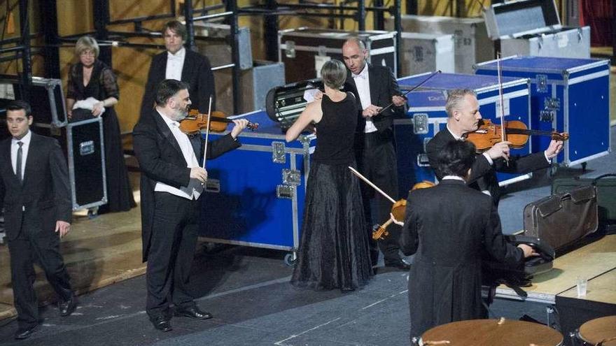 Músicos de la Sinfónica se preparan tras el escenario antes de una actuación.