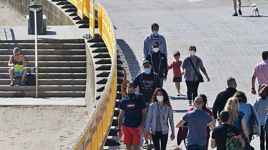 Ciudadanos caminan por el paseo marítimo coruñés en la zona de Riazor.