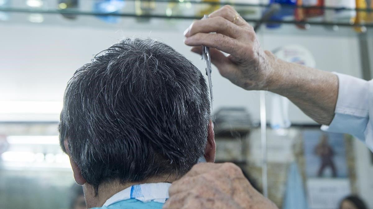 Un peluquero atiende a un cliente.