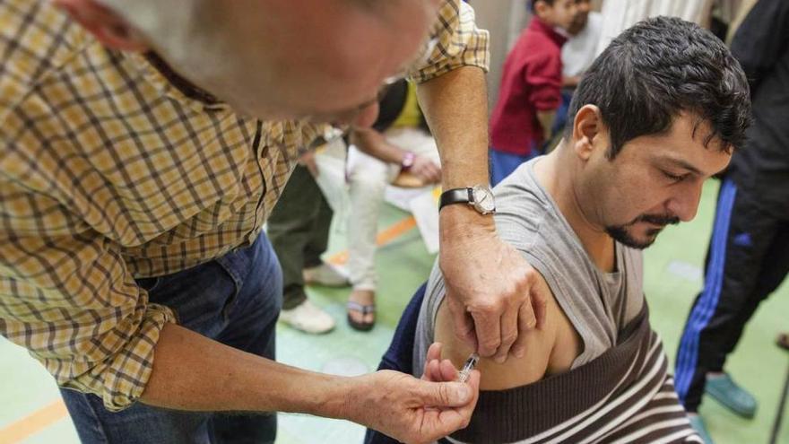 Un médico voluntario alemán vacuna a un refugiado en un centro de acogida de Stuttgart.