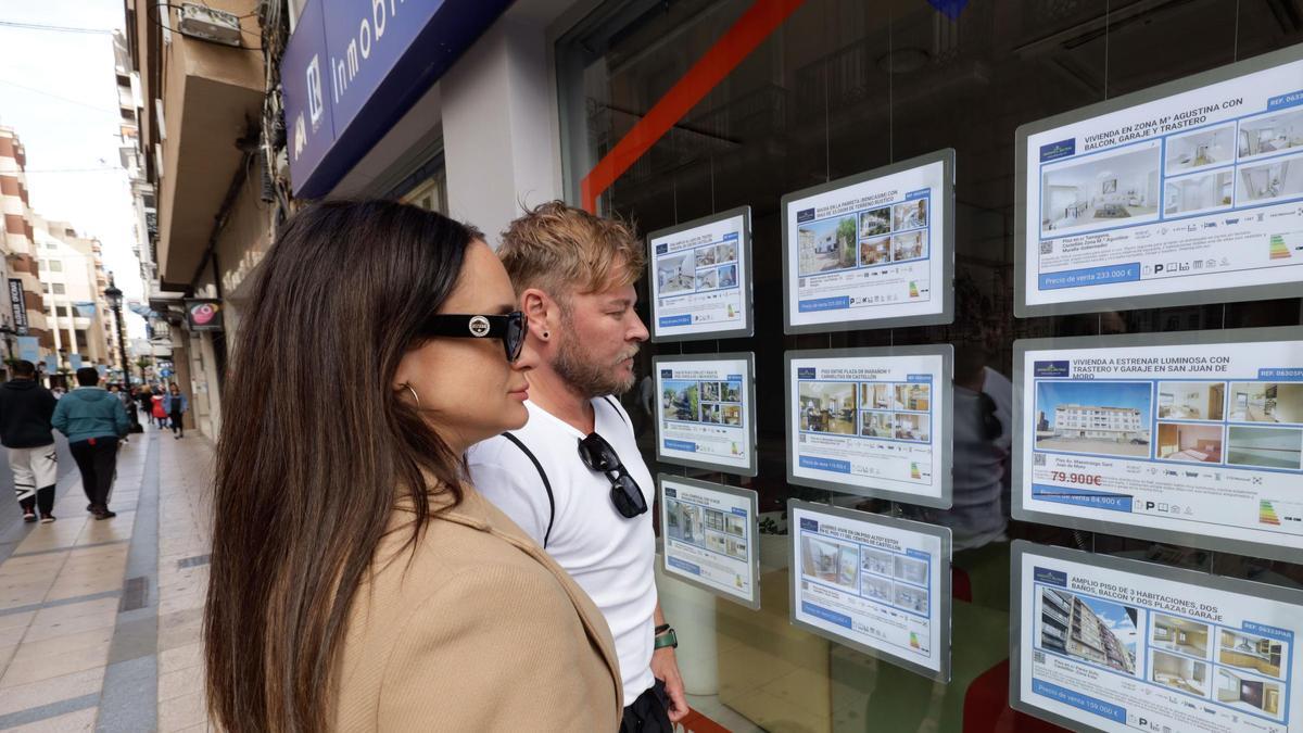 Una pareja mira los anuncios del escaparate de una agencia inmobiliaria de Castelló.