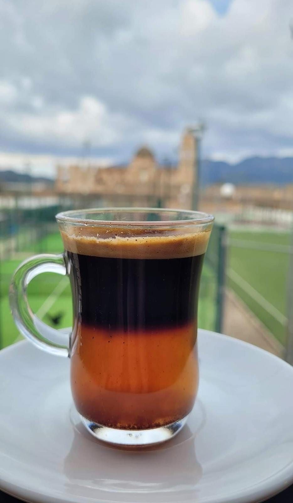 Imagen de un carajillo &#039;cremaet&#039; del Bar Poliesportiu de Simat de la Valldigna, con el monasterio del municipio de fondo.