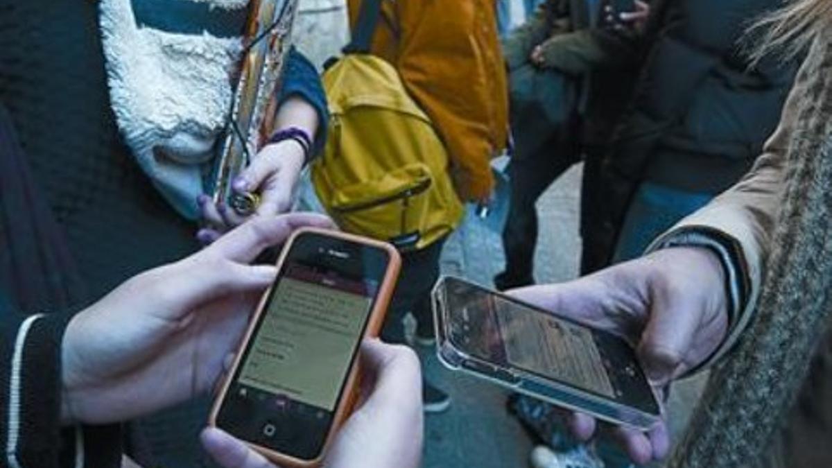 Unos jóvenes consultan sus teléfonos móviles en un instituto de Barcelona