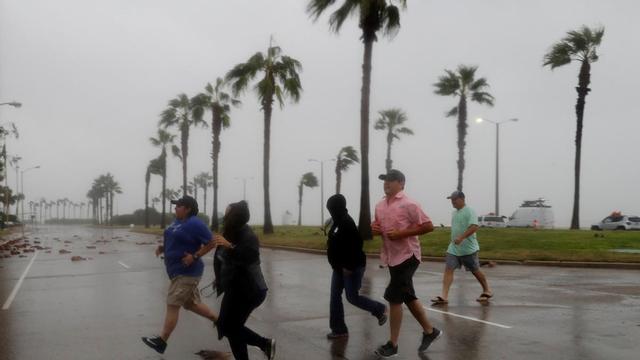 Un grupo de personas corre a refugiarse ante la llegada del huracán 'Harvey0, en Corpus Christi (Texas).