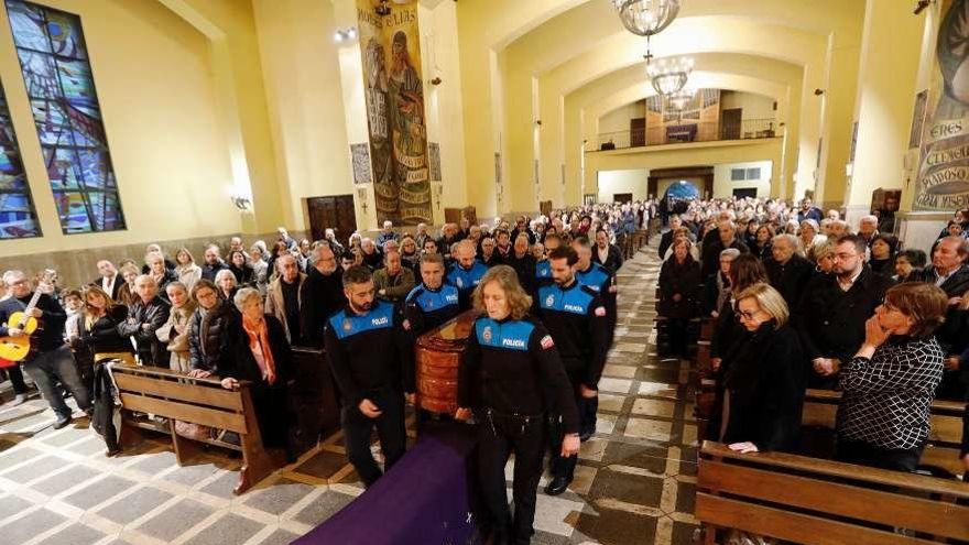 Siete policías locales introducen el cuerpo de Ponga en la iglesia de Llaranes. A la derecha, en primera fila, la alcaldesa, Mariví Monteserín, y su antecesora, Pilar Varela, con Adrián Barbón, líder del PSOE asturiano, detrás. A la izquierda, la viuda, Juana María de Esparta, y sus hijos Paula, Belén y Bernardo Ponga.