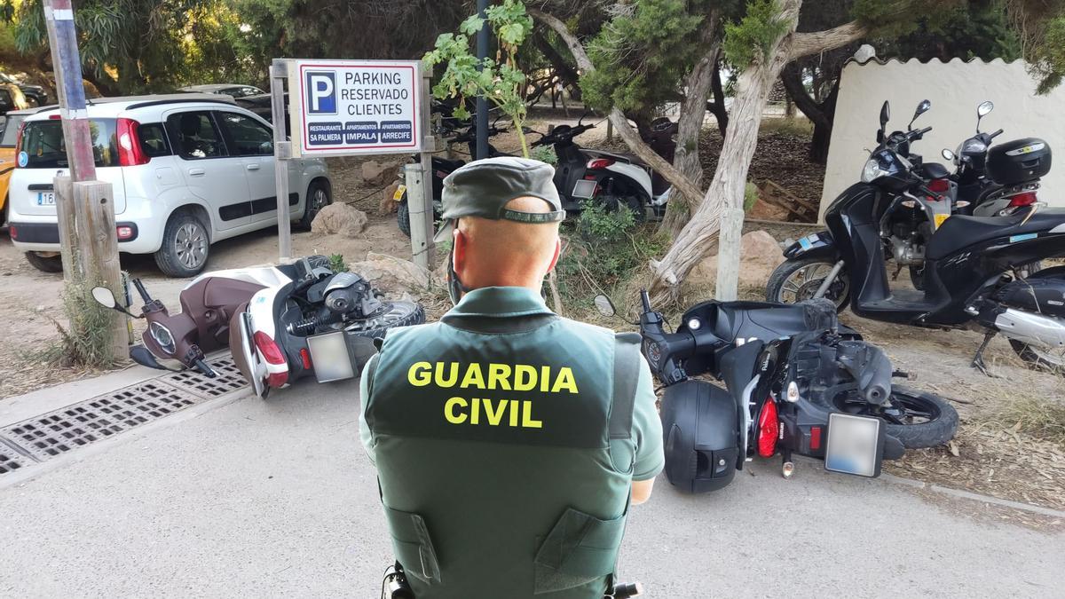 Un agente de la Guardia Civil frente a varios de los vehículos dañados por el detenido