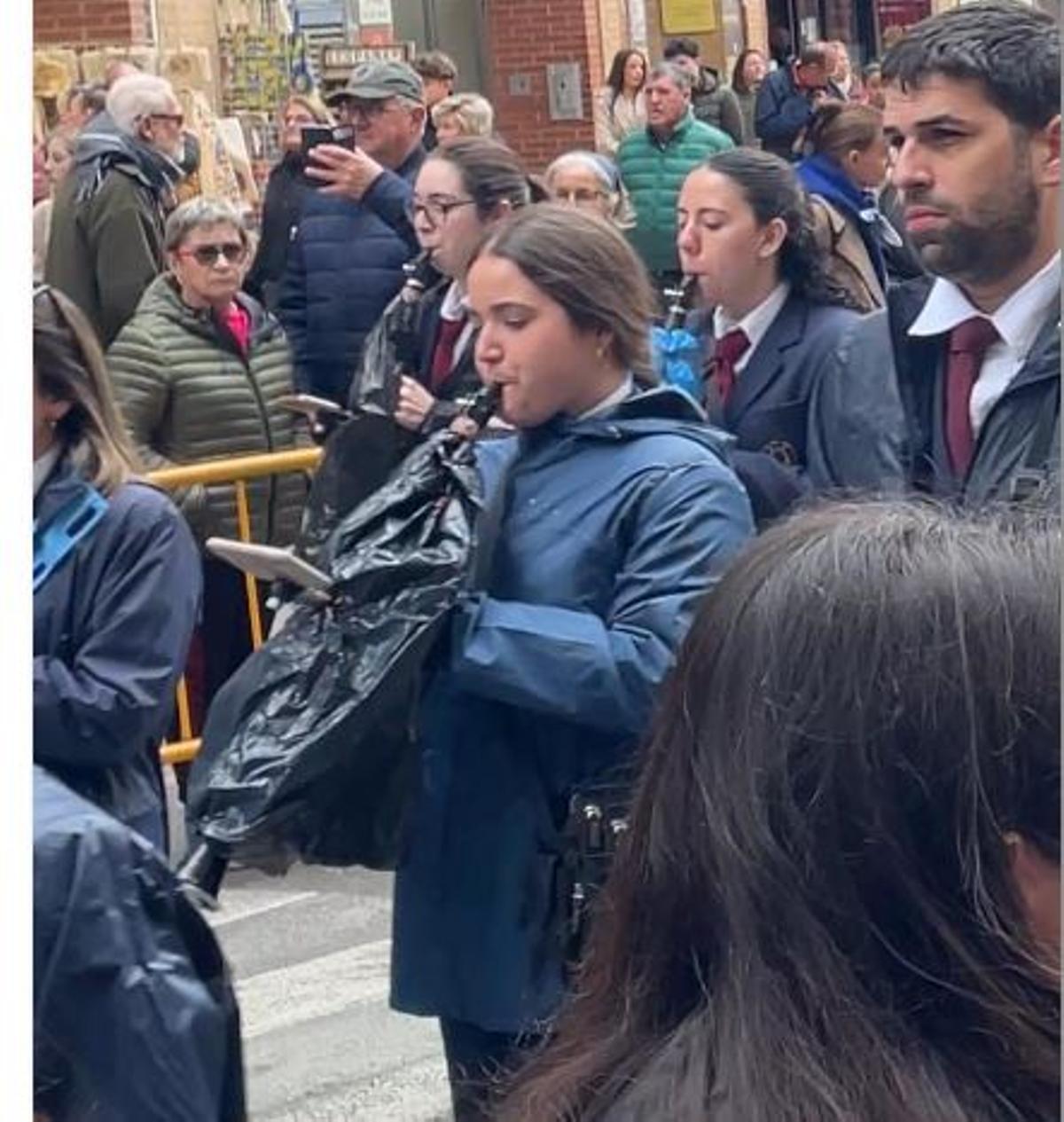 Integrantes de una banda de música protegen con bolsas de basura el instrumental